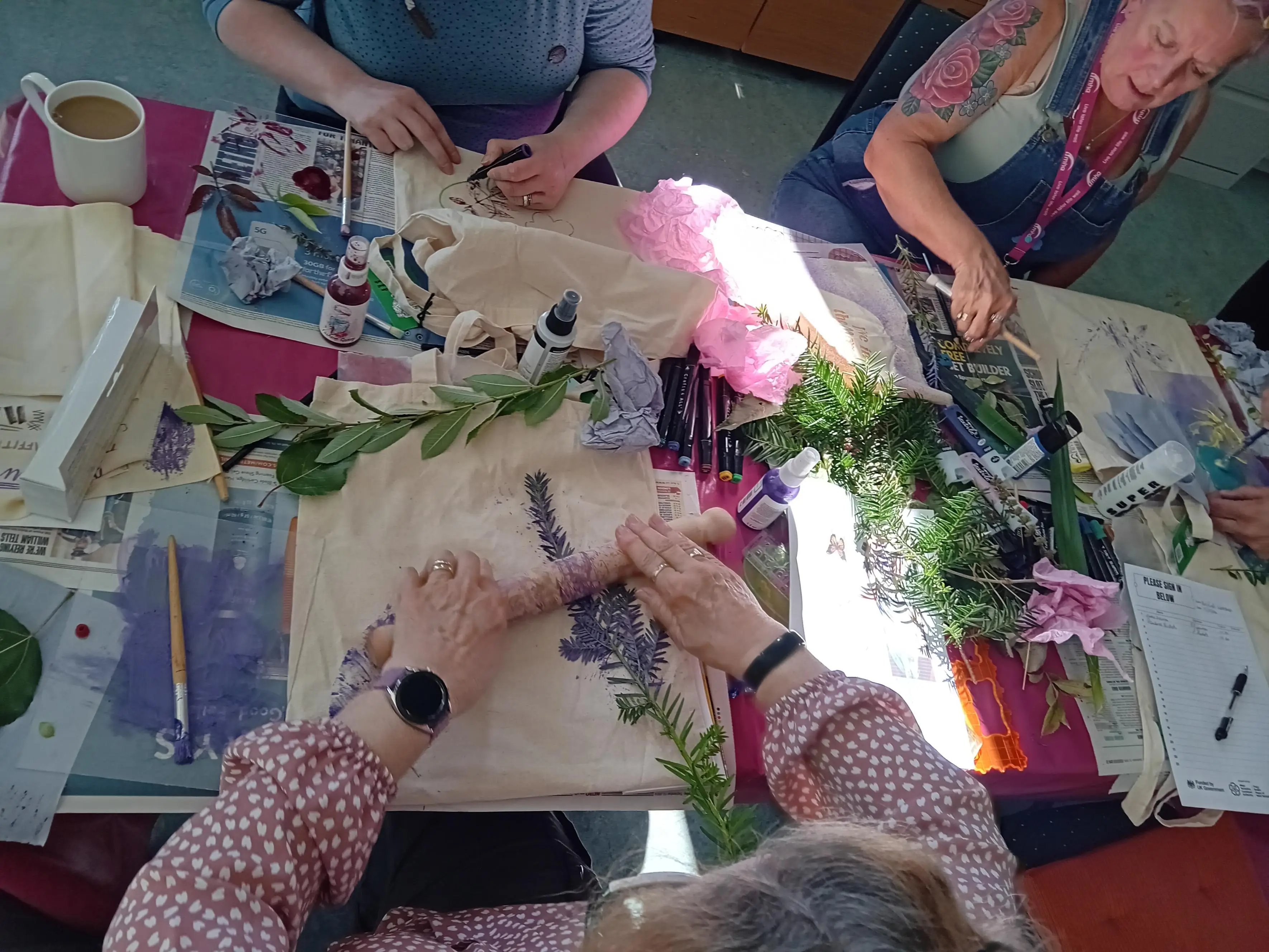 a crafter using a rolling pin to transfer ink from leaf to fabric