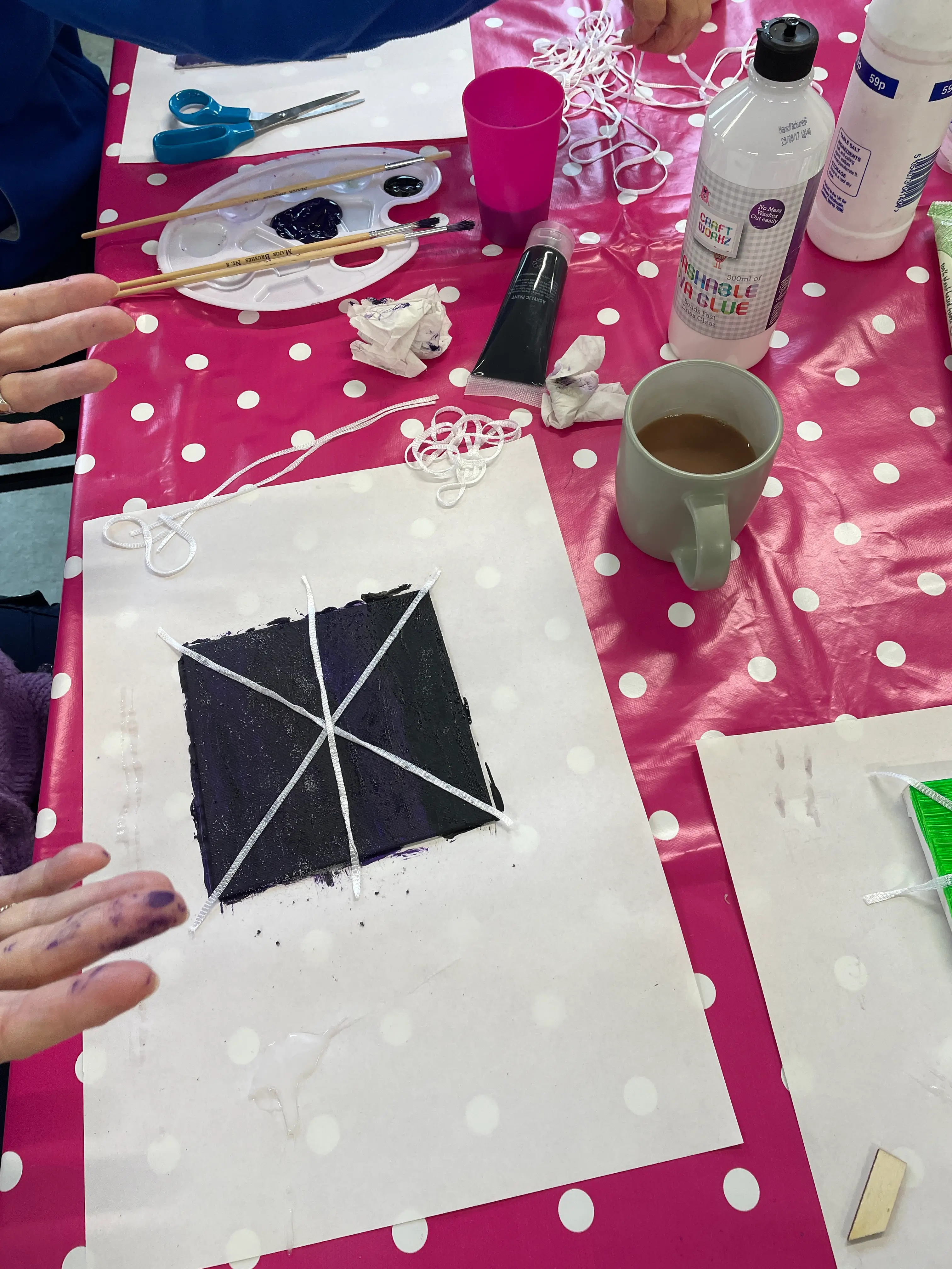 a half-painted mini canvas and the artist with purple fingertips a half-painted mini canvas and the artist with purple fingertips